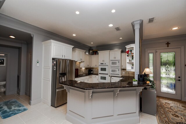 kitchen with a breakfast bar area, white appliances, dark stone counters, ornamental molding, and kitchen peninsula