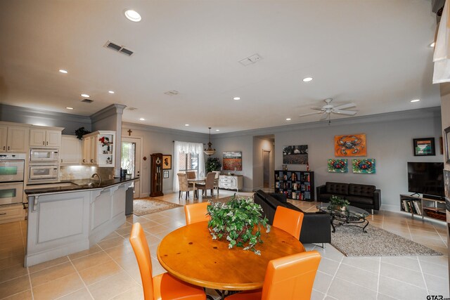 tiled dining room with ceiling fan and crown molding