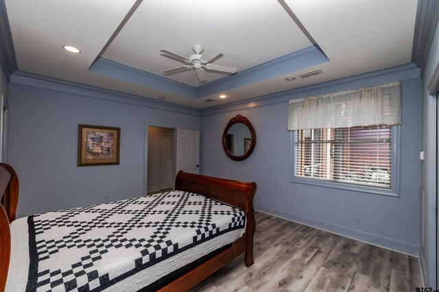 bedroom featuring a raised ceiling, crown molding, and hardwood / wood-style floors