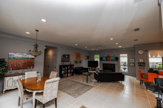 tiled dining space featuring a fireplace, ornamental molding, and ceiling fan