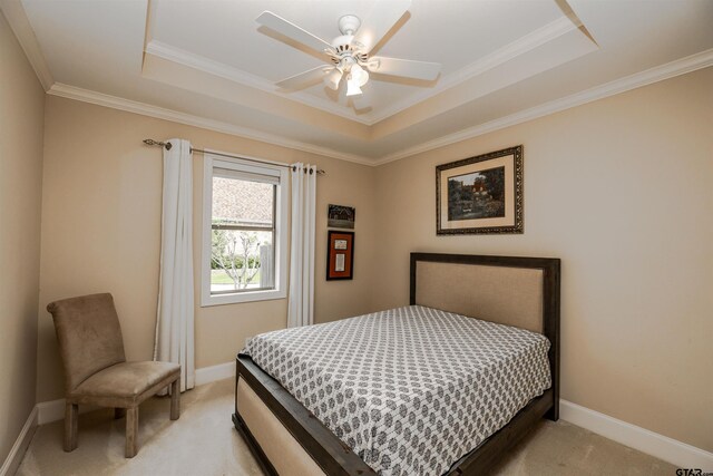 carpeted bedroom featuring ceiling fan, ornamental molding, and a raised ceiling