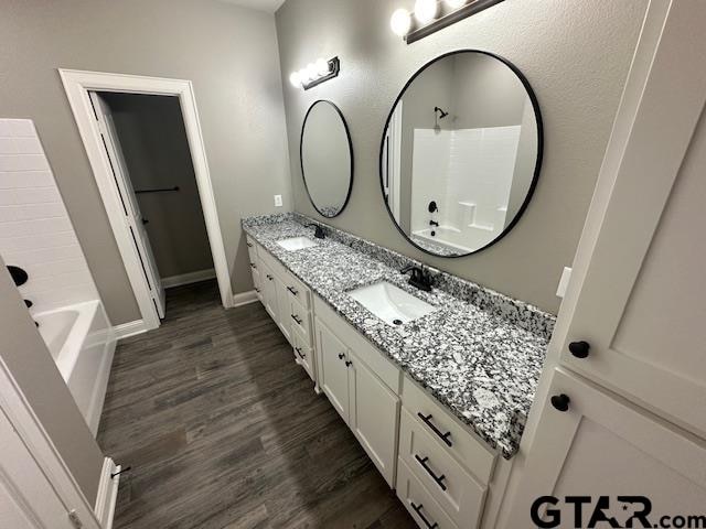 bathroom with hardwood / wood-style flooring, vanity, and tub / shower combination