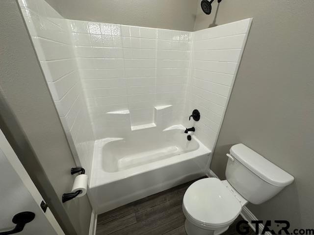 bathroom with hardwood / wood-style flooring, toilet, and bathtub / shower combination