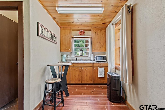 5766 Fm 279, Ben Wheeler, TX 75754 - kitchen with wood finish floors, a textured wall, light countertops, brown cabinetry, and wooden ceiling