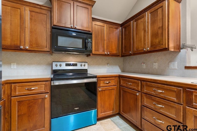 kitchen with tasteful backsplash, vaulted ceiling, stainless steel range with electric stovetop, and light tile patterned flooring