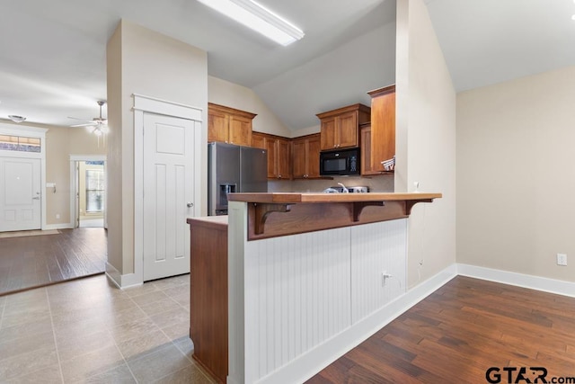 kitchen with ceiling fan, a kitchen breakfast bar, kitchen peninsula, stainless steel fridge, and lofted ceiling