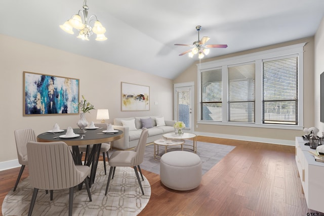 living room with ceiling fan with notable chandelier, hardwood / wood-style flooring, and vaulted ceiling