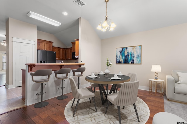 dining room with ceiling fan with notable chandelier, light hardwood / wood-style floors, and lofted ceiling