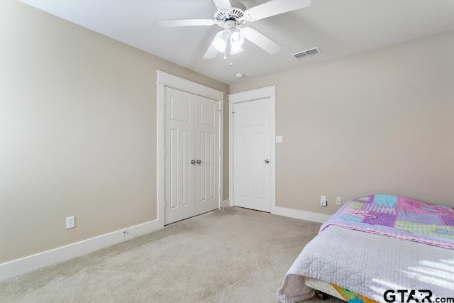 bedroom with ceiling fan, light carpet, and a closet