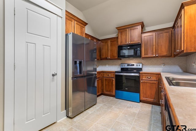 6023 Grace Ave, Tyler, TX 75707 - kitchen with stainless steel appliances, vaulted ceiling, light countertops, decorative backsplash, and brown cabinetry