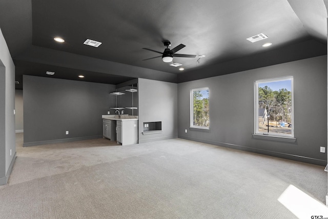 unfurnished living room with sink, light carpet, and ceiling fan