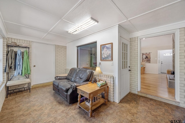 sitting room with hardwood / wood-style floors and brick wall