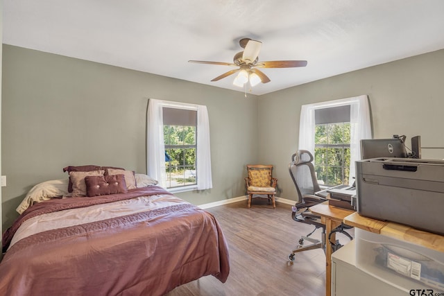 bedroom featuring ceiling fan, multiple windows, and light wood-type flooring