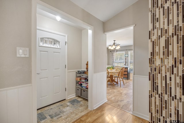 foyer featuring wood-type flooring, a chandelier, and vaulted ceiling