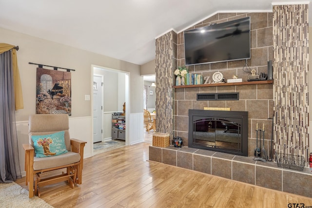 living room with tile walls, hardwood / wood-style floors, lofted ceiling, and a tile fireplace