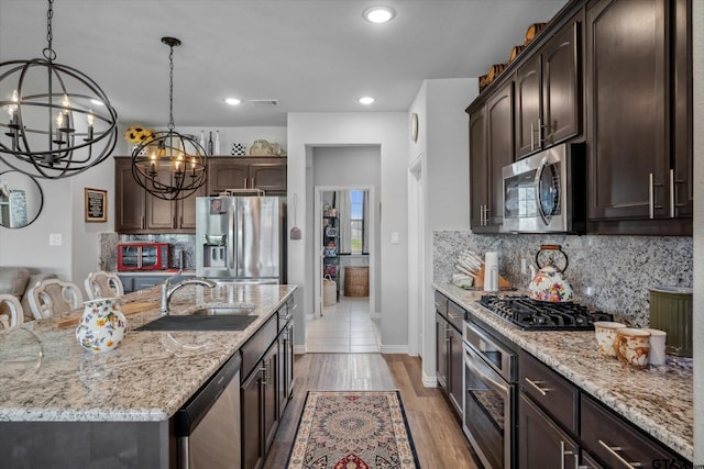 kitchen featuring an inviting chandelier, a sink, visible vents, dark brown cabinetry, and appliances with stainless steel finishes