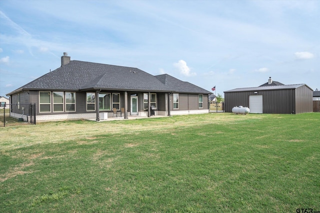 back of property with a chimney, fence, a yard, and an outbuilding