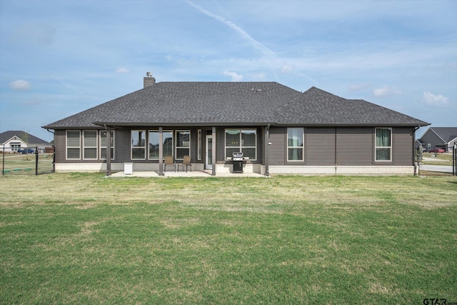 back of house with fence, a shingled roof, a patio area, and a yard
