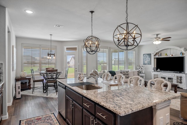 kitchen featuring dishwasher, dark brown cabinetry, a sink, open floor plan, and dark wood-style floors