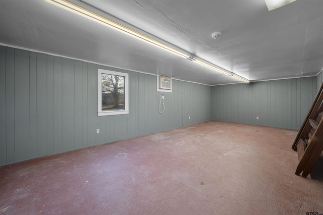 basement featuring wooden walls and a wall unit AC