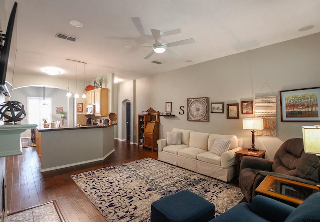 living area featuring visible vents, arched walkways, ceiling fan, and dark wood-style flooring