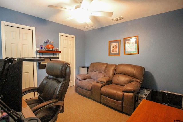 carpeted home office with a ceiling fan and visible vents