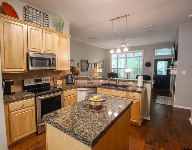 kitchen with tile counters, light brown cabinets, a sink, a peninsula, and appliances with stainless steel finishes