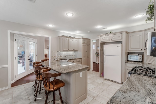 18400 Woodhollow Dr, Flint, TX 75762 - kitchen with freestanding refrigerator, a sink, light tile patterned floors, a peninsula, and a breakfast bar area