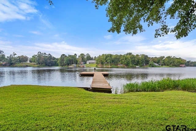 view of dock with a lawn and a water view