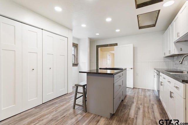 kitchen featuring sink, white cabinets, a kitchen breakfast bar, a center island, and light hardwood / wood-style floors