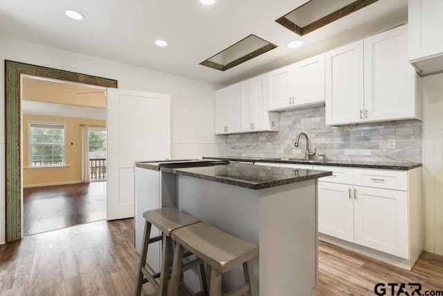 kitchen with white cabinetry, a center island, sink, and a kitchen bar