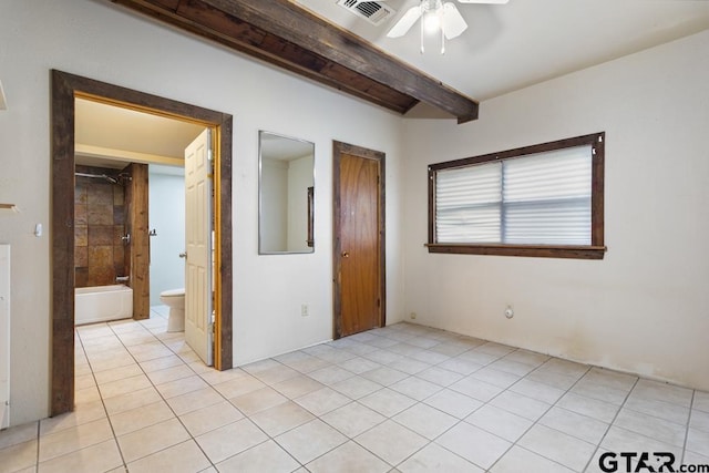 unfurnished bedroom with light tile patterned flooring, connected bathroom, ceiling fan, and beam ceiling