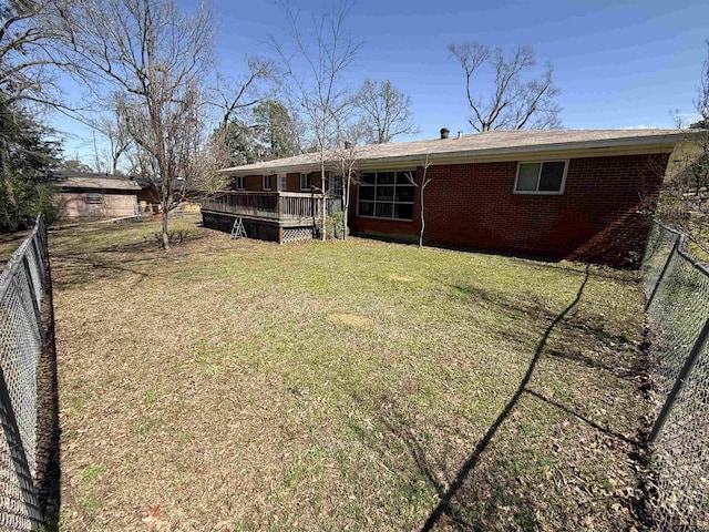 back of property with a deck, a yard, fence, and brick siding