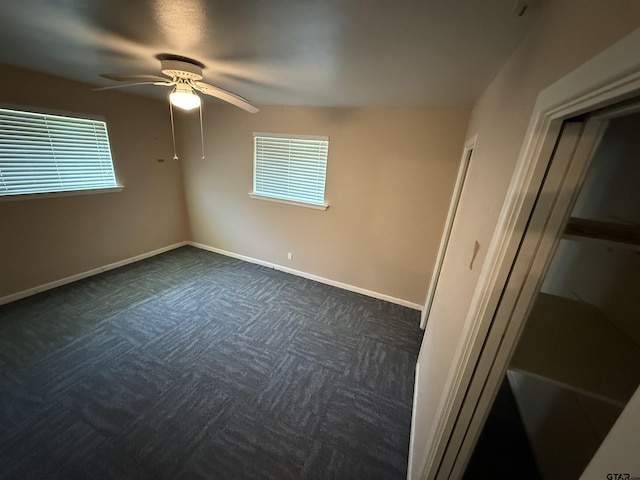 spare room with baseboards, dark carpet, plenty of natural light, and a ceiling fan