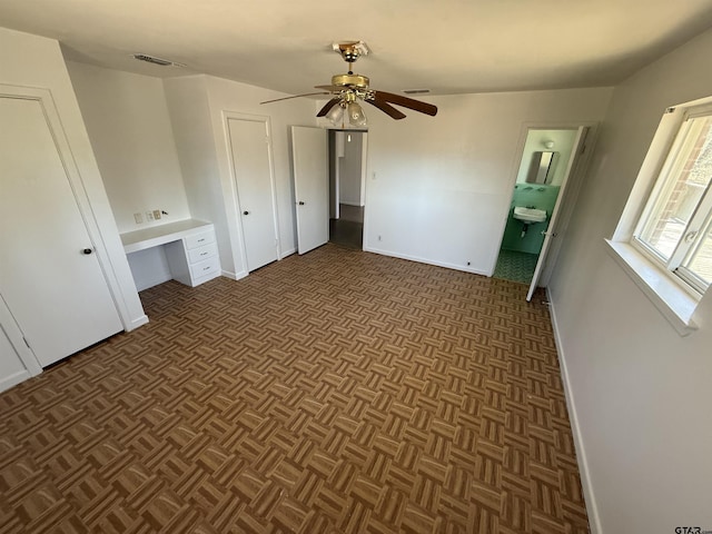 unfurnished bedroom with a ceiling fan, ensuite bath, baseboards, and visible vents