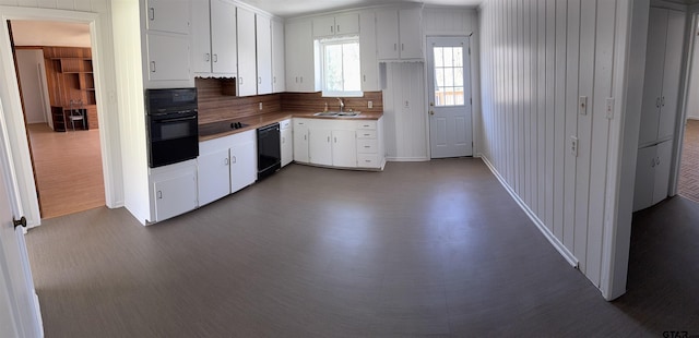 kitchen with dark wood-style floors, a sink, black appliances, white cabinetry, and tasteful backsplash