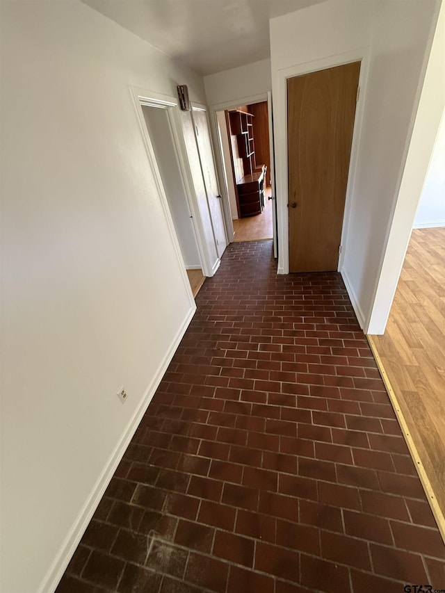 corridor with brick floor and baseboards