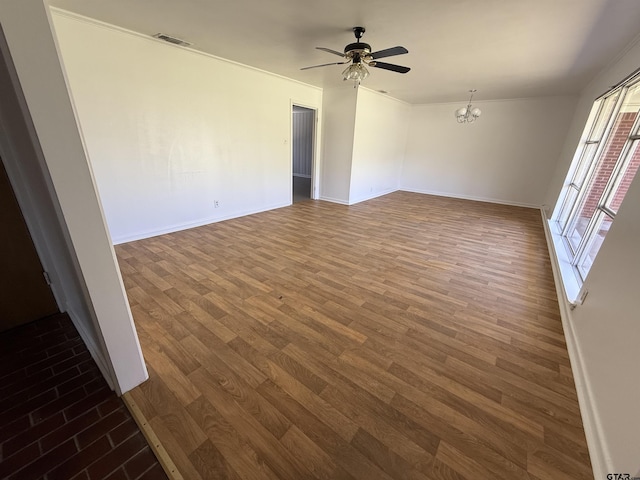 empty room with ceiling fan with notable chandelier, wood finished floors, visible vents, and baseboards