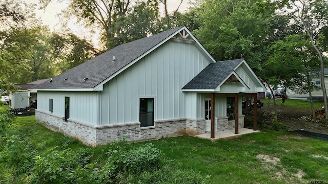1212 N Albertson Ave, Tyler, TX 75702 - rear view of house featuring brick siding, roof with shingles, a lawn, and board and batten siding
