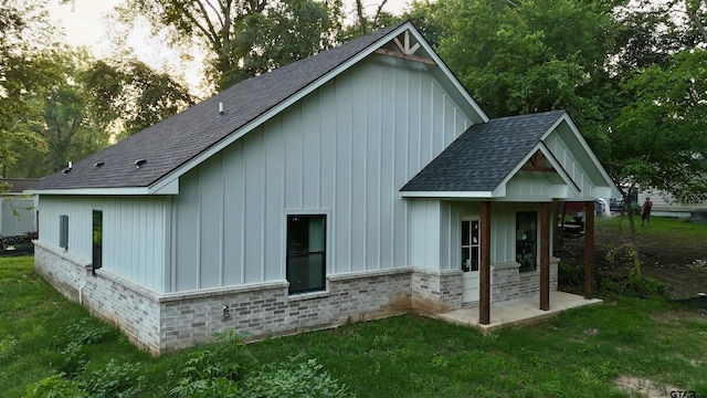 1212 N Albertson Ave, Tyler, TX 75702 - rear view of property with a shingled roof, board and batten siding, a lawn, and brick siding