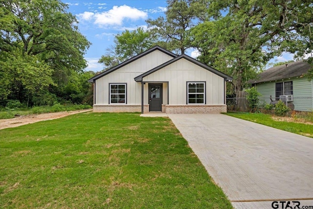 view of front facade with fence, board and batten siding, brick siding, and a front yard