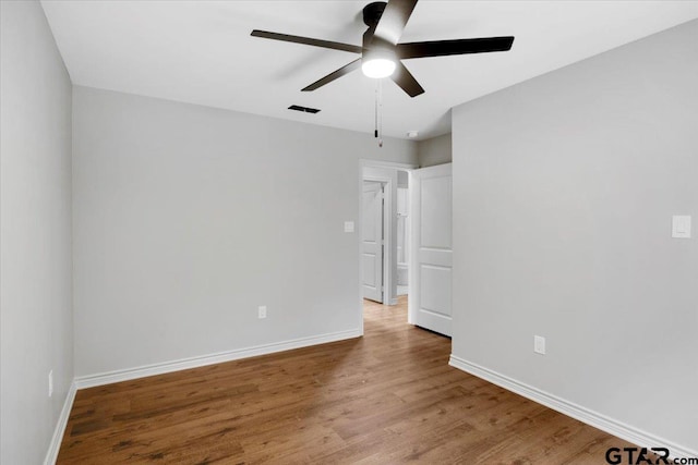 unfurnished room with baseboards, a ceiling fan, wood finished floors, and visible vents
