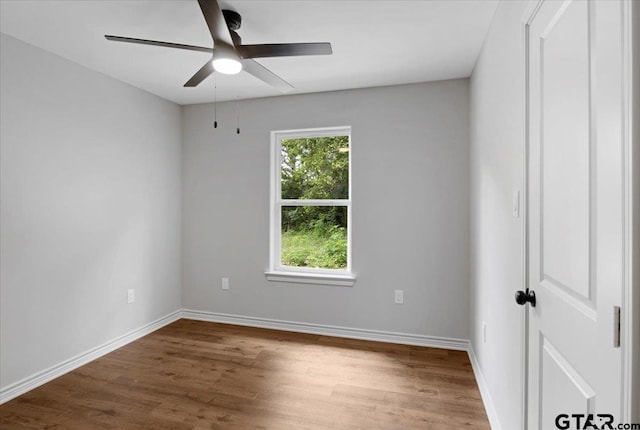 spare room with baseboards, ceiling fan, and wood finished floors