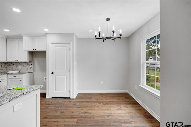 unfurnished dining area with dark wood-style flooring, a notable chandelier, a wealth of natural light, and recessed lighting