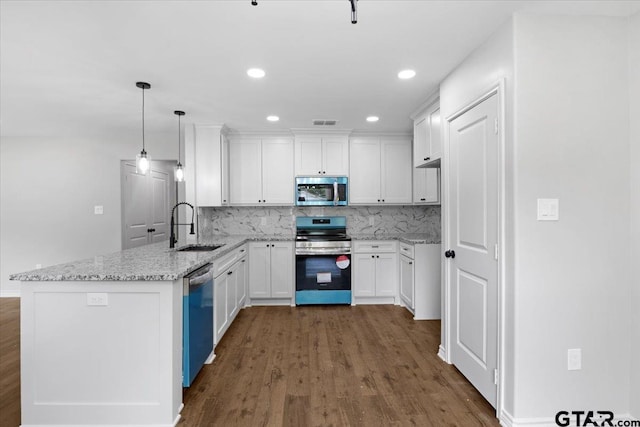 kitchen with decorative backsplash, dark wood finished floors, a sink, a peninsula, and stainless steel appliances