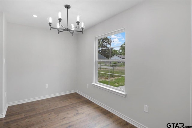 unfurnished dining area featuring dark wood-style flooring, baseboards, a chandelier, and recessed lighting