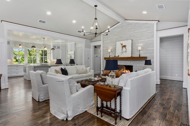 living room with lofted ceiling with beams, a stone fireplace, dark wood-type flooring, and a chandelier