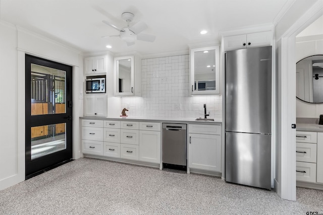 kitchen with crown molding, decorative backsplash, ceiling fan, white cabinetry, and stainless steel appliances