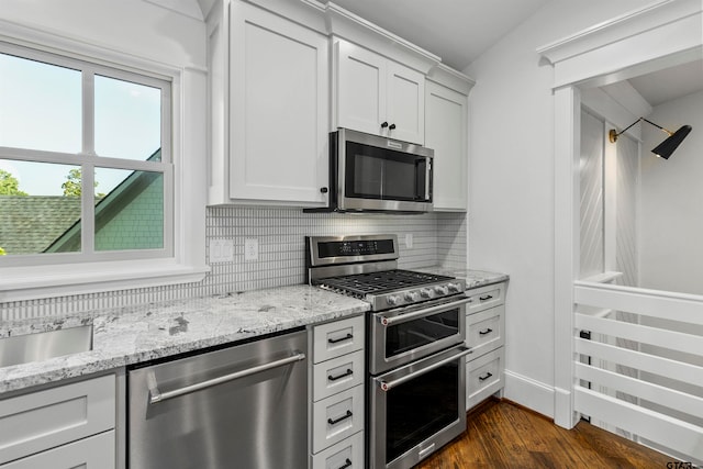 kitchen with backsplash, white cabinetry, and stainless steel appliances