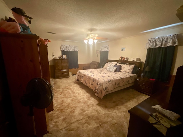 bedroom with a textured ceiling, light carpet, ceiling fan, and crown molding